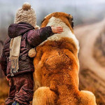 Kind steht entspannt neben einem grosen Hund